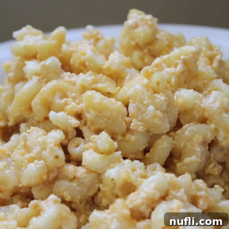 Creamy Crockpot macaroni and cheese served in a pristine white bowl, a classic comfort food side.