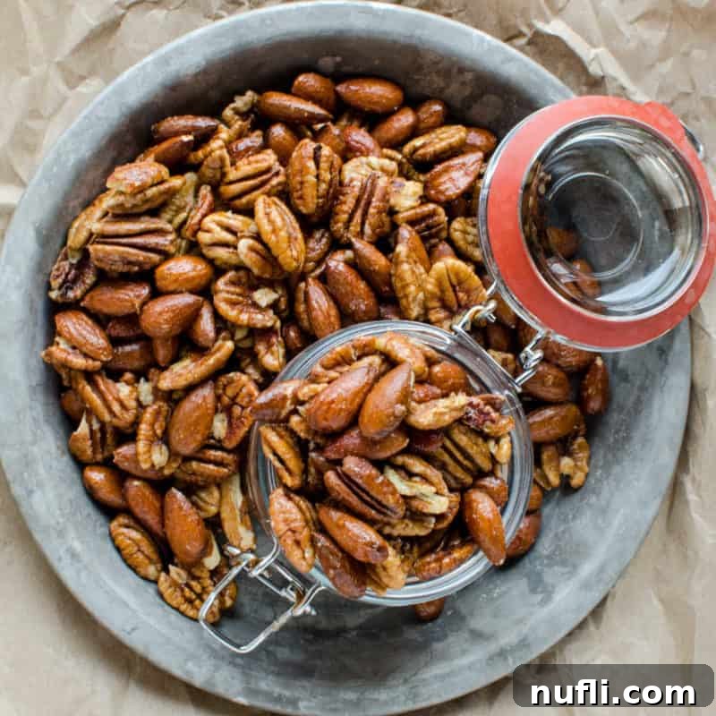 sweet and spicy nuts spread on a silver tray with a glass jar