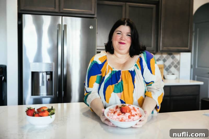 Strawberry Cloud Delight 11 Tammilee holding a bowl of Strawberry Fluff in home kitchen next to a bowl of strawberries