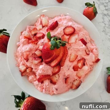 Strawberry Cloud Delight 12 Strawberry fluff salad in a white bowl with cut strawberries for garnish
