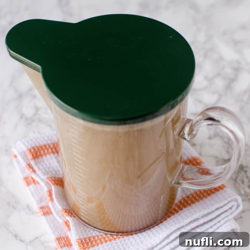 Nutritious Pork Bone Broth in a glass container with a green lid, ready for use.