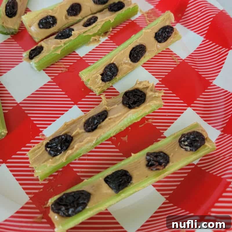 Classic Ants on a Log: Celery sticks filled with peanut butter and topped with raisins, served on a cheerful red and white plate.