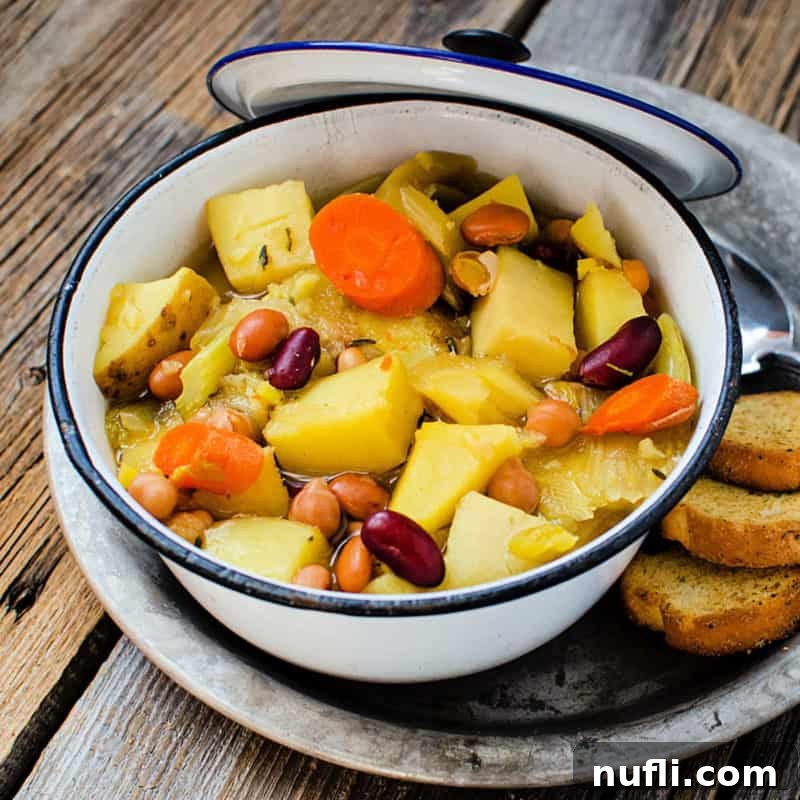 A vibrant Crockpot Vegetarian Soup, brimming with carrots, beans, and potatoes, cooking in a pot.