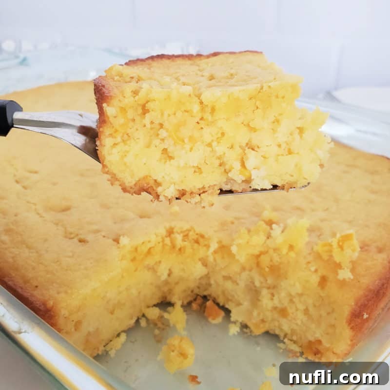 Square of Cornbread on a serving spoon over a dish of cornbread