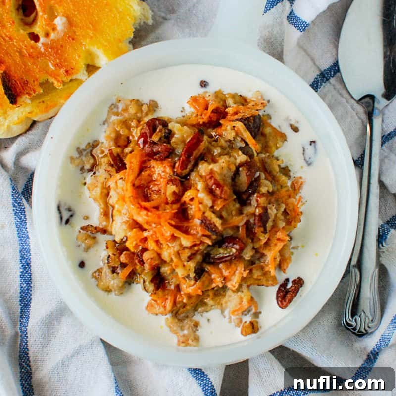 A bowl of creamy Carrot Cake Oatmeal, adorned with spices, next to a spoon and a bagel, hinting at a delightful breakfast.