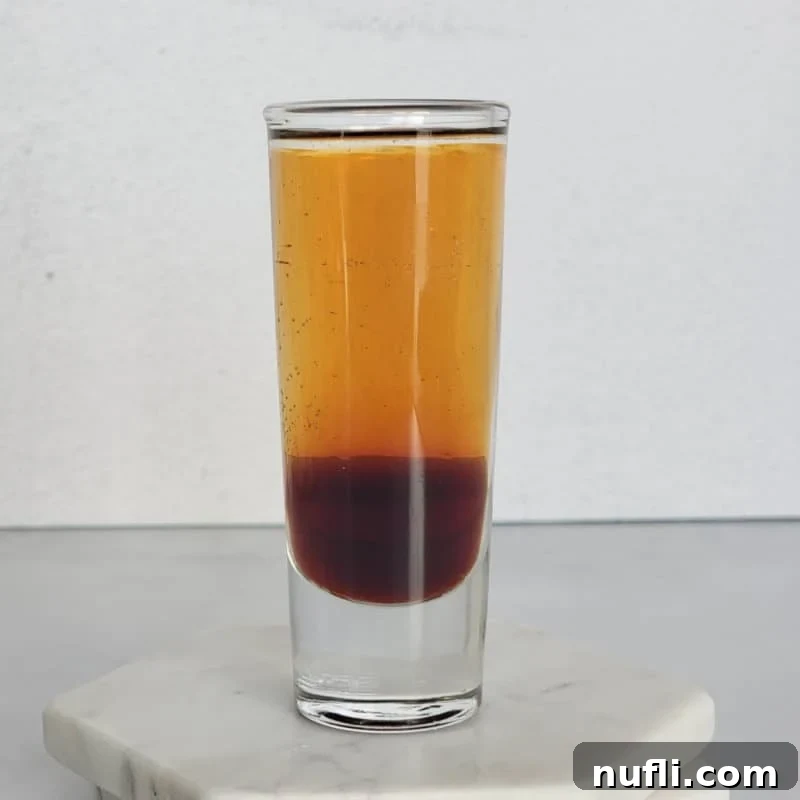 A visually striking layered Mind Eraser shot in a tall glass, resting on elegant coasters.