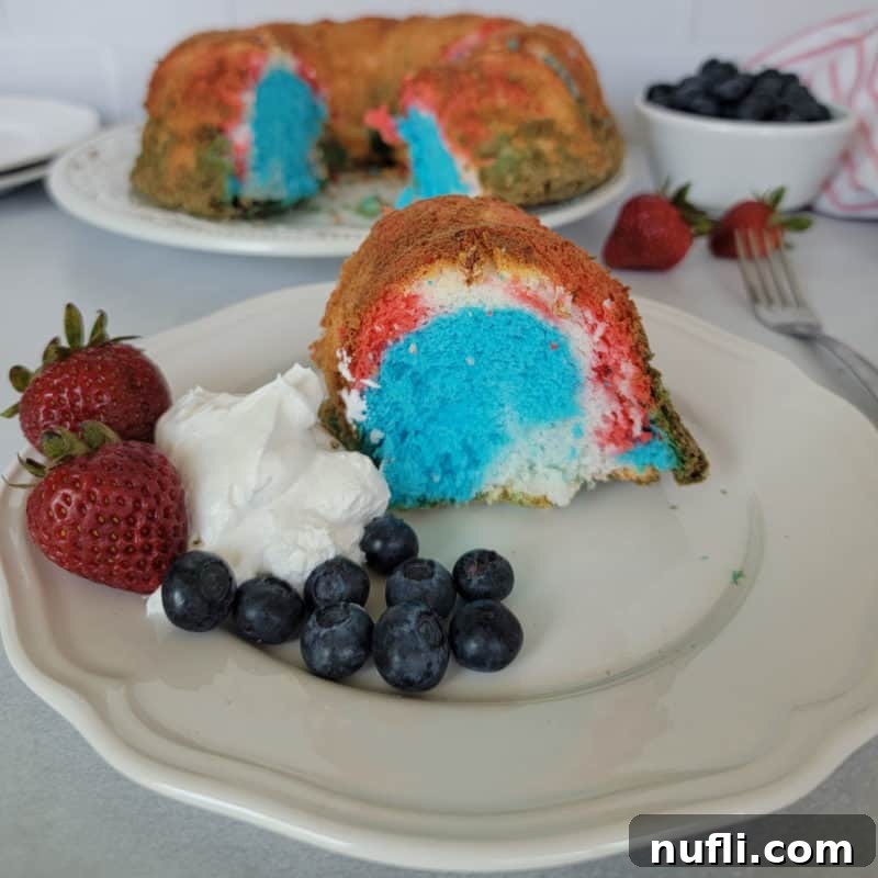 Red white and blue angel food cake next to strawberries, blueberries, and whipped cream