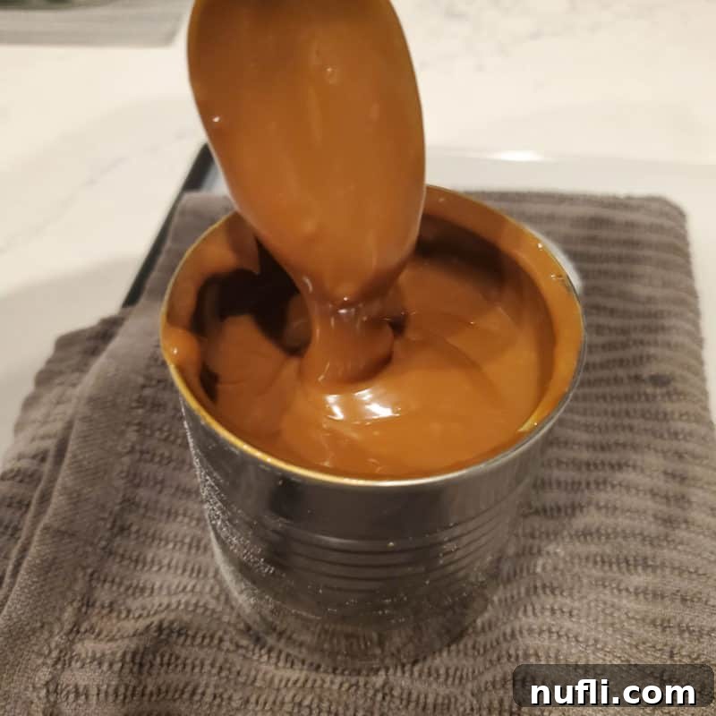 Spoon covered in caramel sauce coming out of a jar