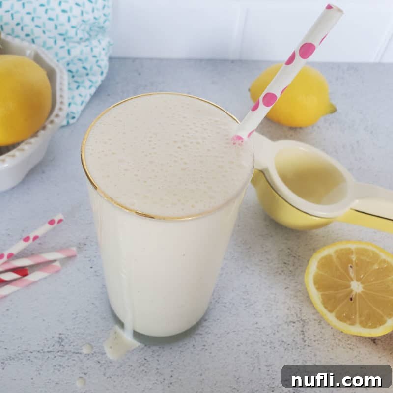 Frosted lemonade in a tall glass with a polka dot straw, surrounded by lemons