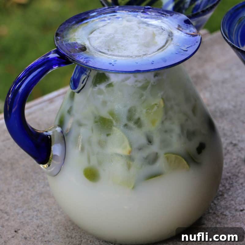 Brazillian Lemonade in a glass pitcher with limes