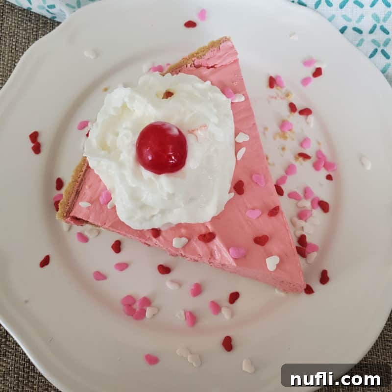 Slice of pink Kool Aid Pie on a white plate with heart sprinkles