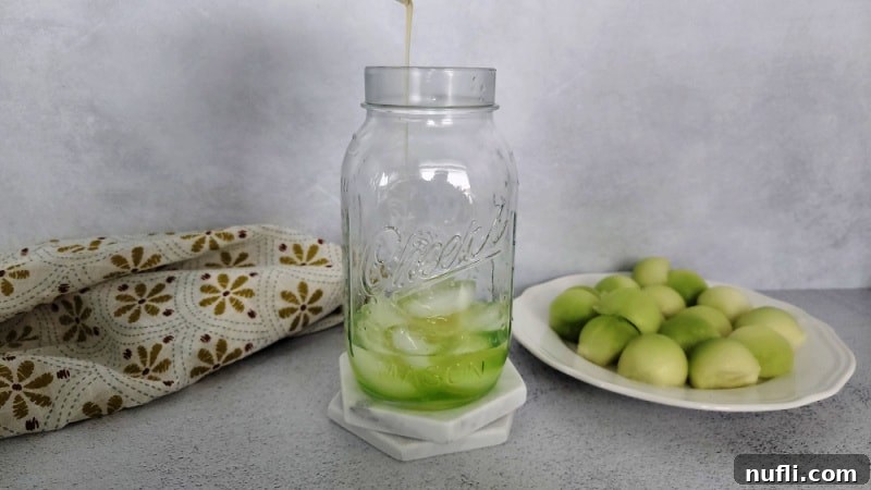Pouring green Midori melon liqueur into a cocktail shaker filled with ice, next to a plate of fresh melon slices.