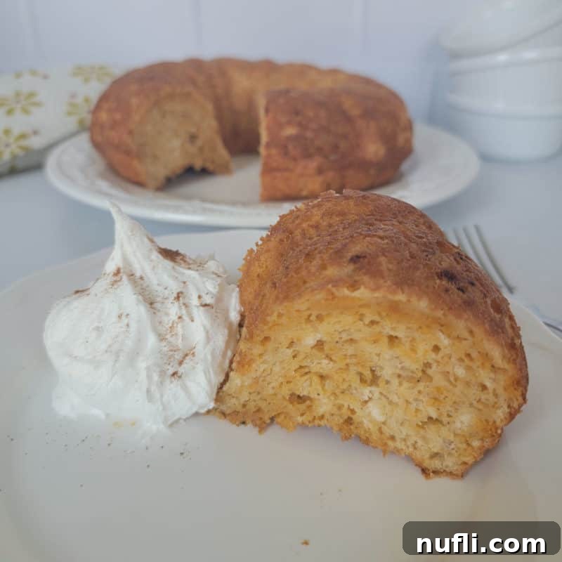 Cozy Autumn Treats You'll Love 5 A delicate slice of pumpkin angel food cake positioned beside a dollop of fluffy whipped cream, with the full cake gently blurred in the background, highlighting its light and airy texture.