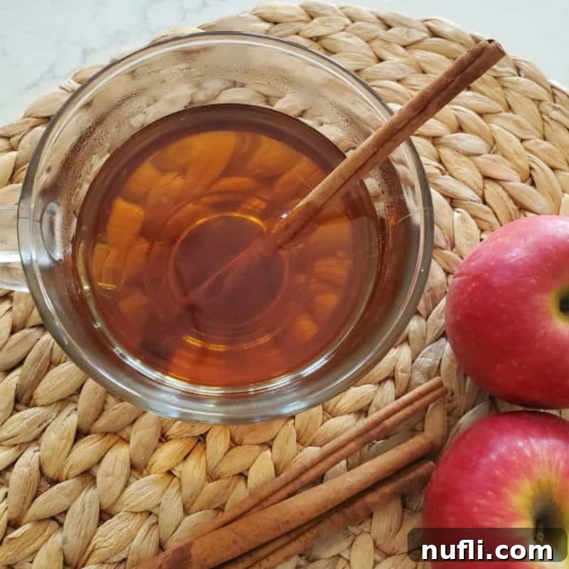 Dozens of Cozy Fall Cocktails for the Perfect Autumn 9 Caramel apple cider in a glass mug next to apples and cinnamon sticks