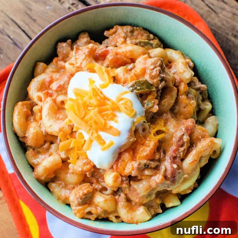 Taco pasta topped with sour cream and cheddar cheese in a bowl