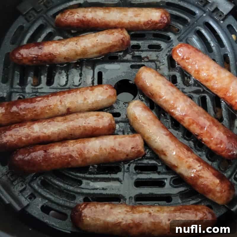 Crispy air-fried sausage links neatly arranged in an air fryer basket, demonstrating a quick and easy cooking method.