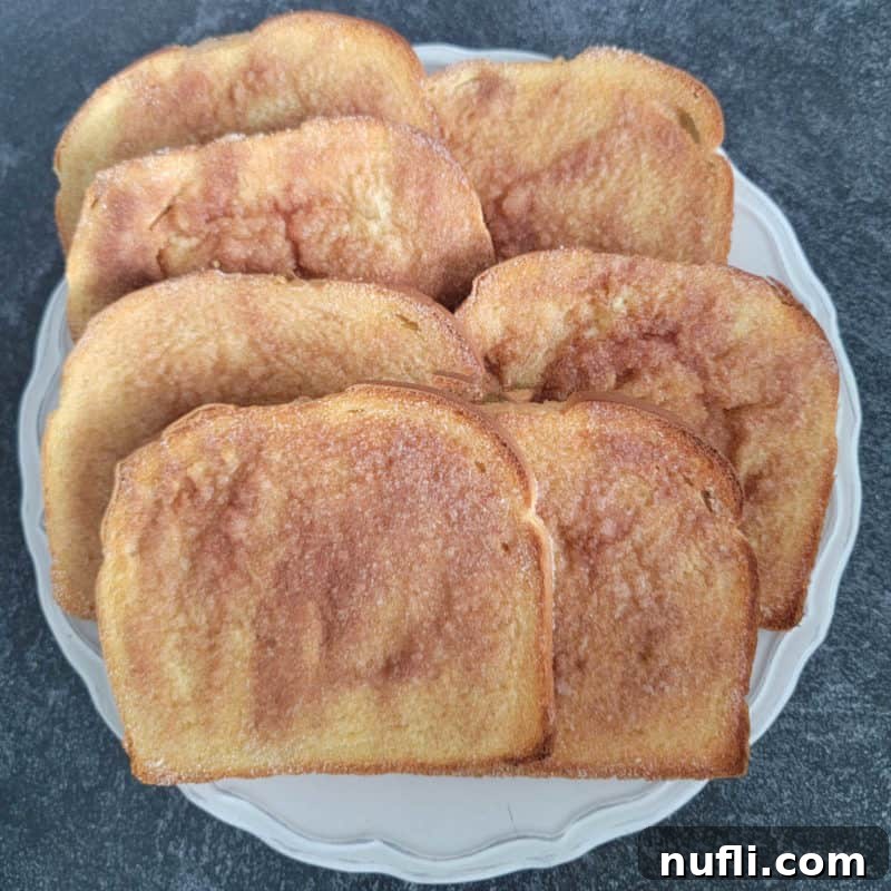 Golden-brown Cinnamon Toast slices arranged on a white plate, a simple yet comforting treat.