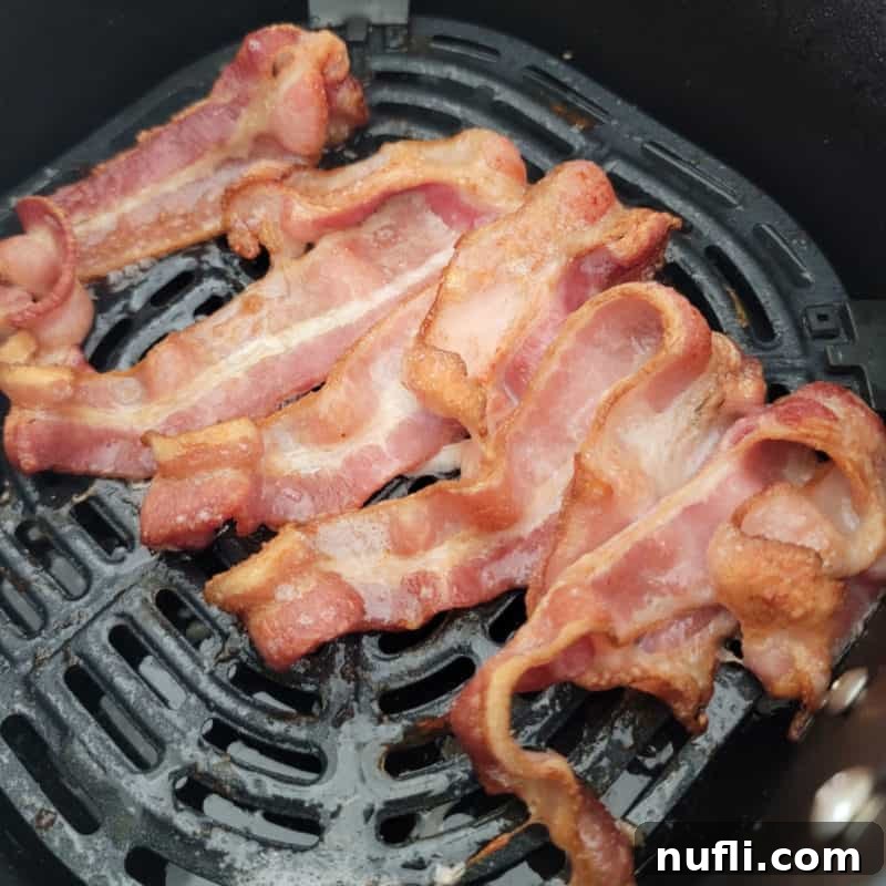 Crispy air-fried bacon strips cooked to perfection and presented in an air fryer basket.