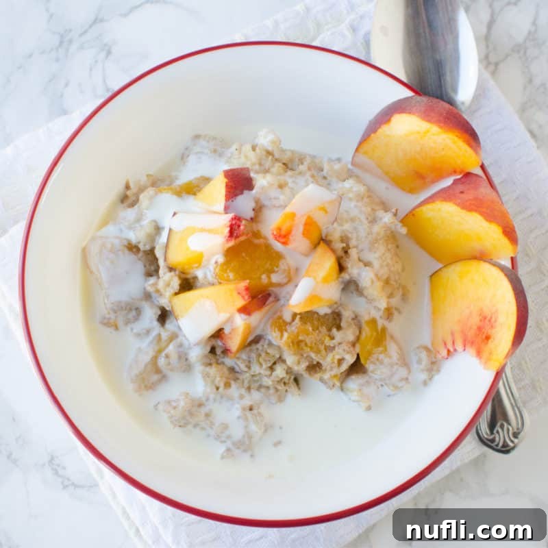 Creamy Peaches and Cream Oatmeal in a white bowl, garnished with fresh sliced peaches.