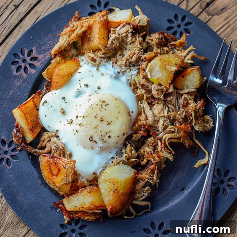 A hearty Pulled Pork Breakfast Hash on a blue plate with a fork, showing its savory ingredients.