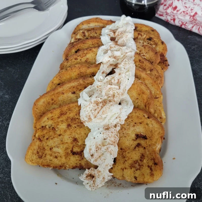Festive Eggnog French Toast topped with eggnog whipped cream on a white platter, ready for a holiday feast.