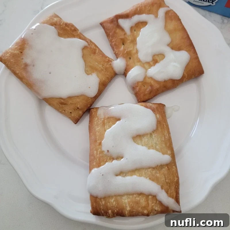 Three perfectly air-fried Toaster Strudels on a white plate, showing their golden hue and flaky texture.