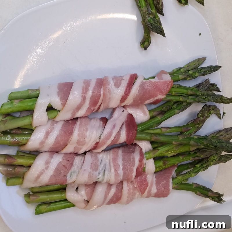 Bacon Wrapped Asparagus on a white plate before cooking