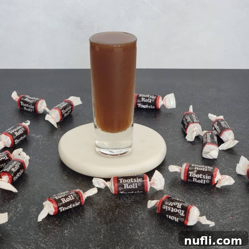Tootsie Roll Shot on a white coaster surrounded by Tootsie Roll Candies