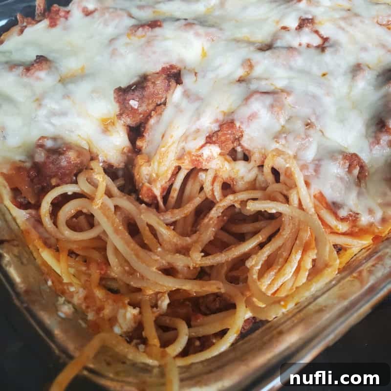 A rich Million Dollar Spaghetti Casserole, bubbling with cheese and sauce, showcased in a glass baking dish.