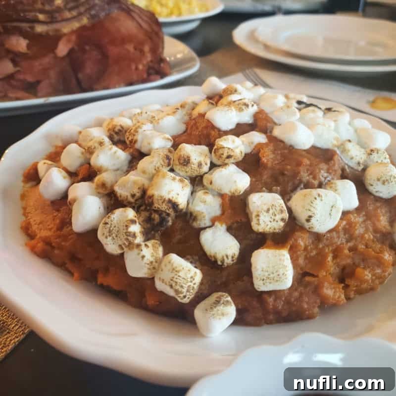 A creamy CrockPot Sweet Potato Casserole topped with mini marshmallows, served in a white bowl.