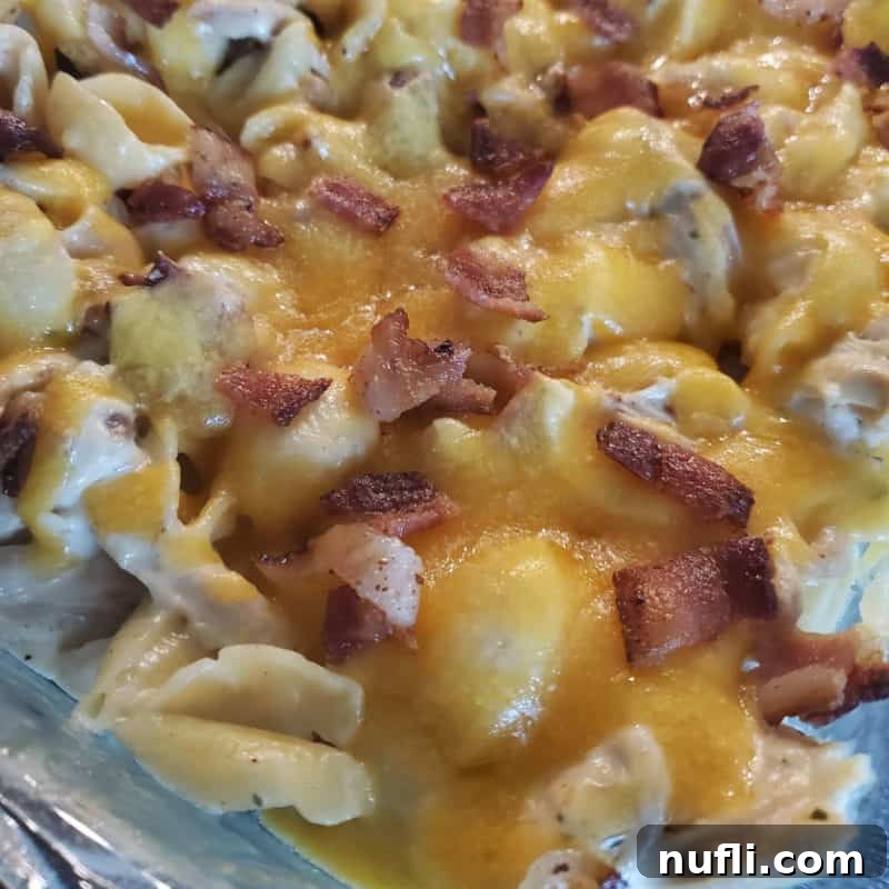 A close-up of Chicken Bacon Ranch Casserole, featuring bubbling melted cheese and crispy bacon bits in a casserole dish.