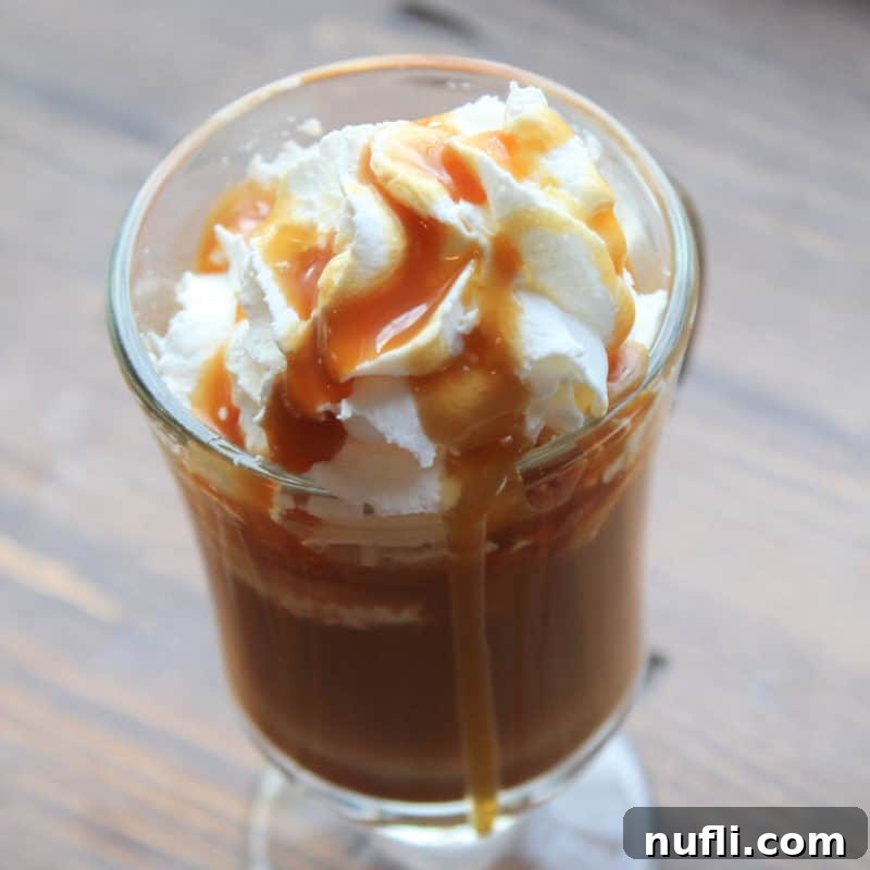 Caramel latte in a glass mug garnished with whipped cream and caramel