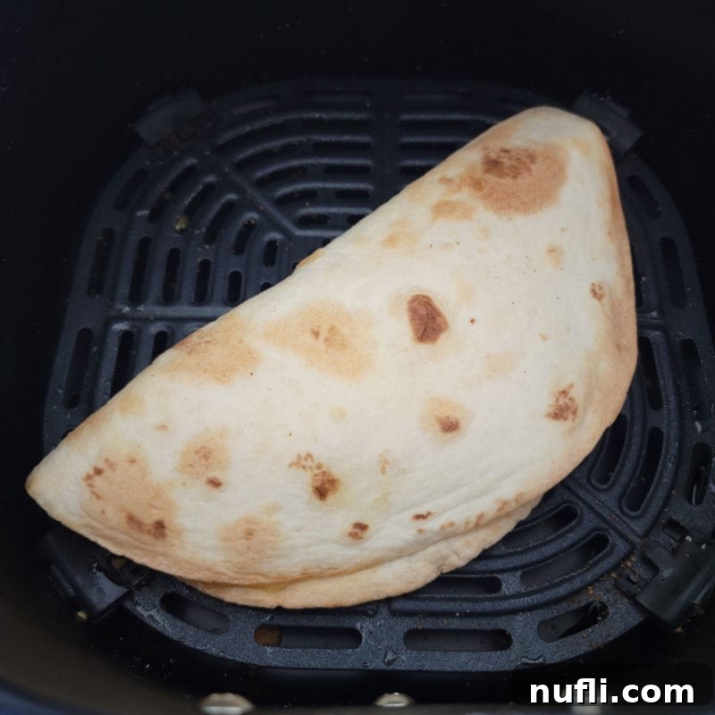 A perfectly air-fried cheese quesadilla, golden and bubbly, nestled in an air fryer basket, ready to be enjoyed.
