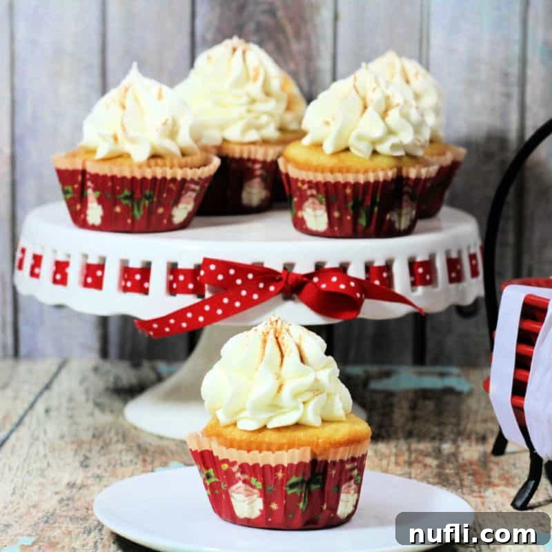 Eggnog Spice Cupcakes arranged on a cake platter and individual white plate, ready for a festive gathering.