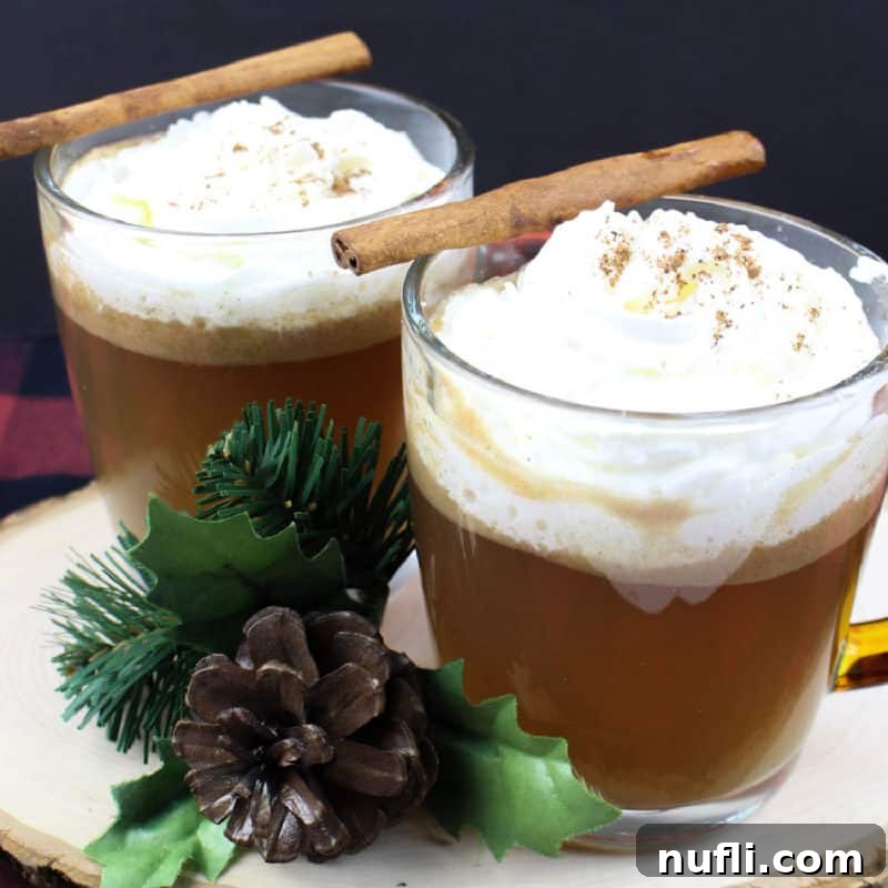 Hot Buttered Rum in glass coffee mugs with cinnamon sticks on a wood board