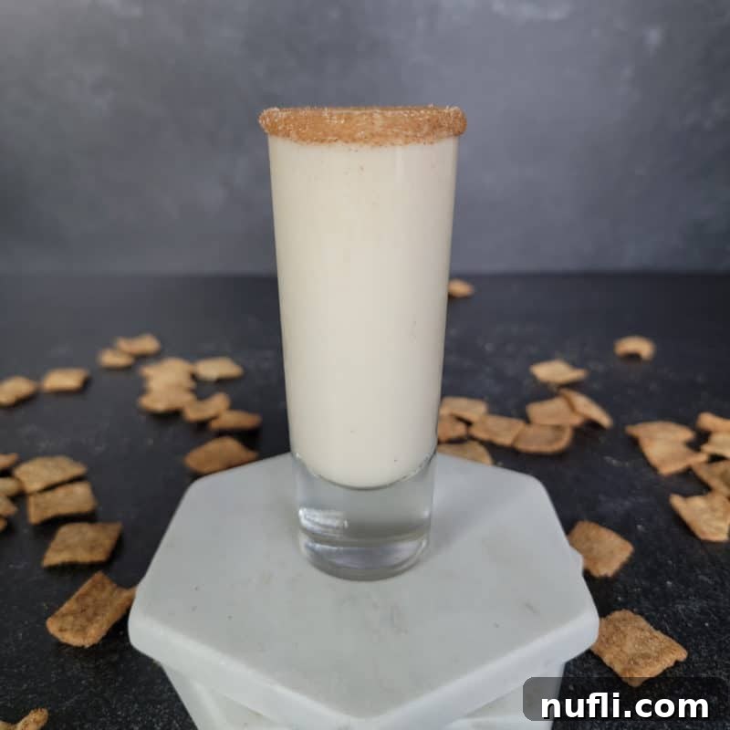 Cinnamon Toast Crunch Shot in a tall shot glass on white coasters surrounded by cereal
