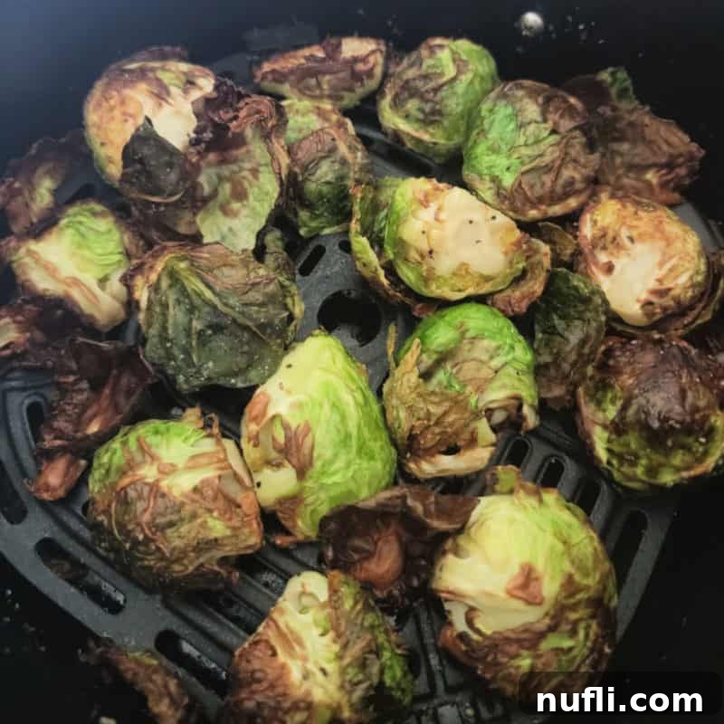 Crispy Air Fryer Brussels Sprouts cooking in the basket of an air fryer.