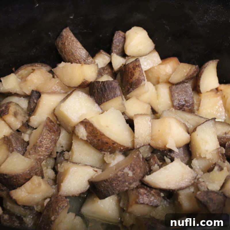 Diced garlic potatoes simmering in a slow cooker, ready to be served.