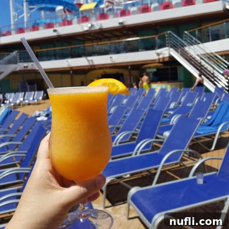 Carnival Cruise Lines Mango Magic Cocktail held in front of blue pool chairs