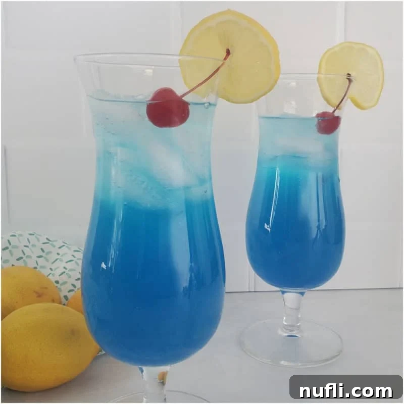 Blue Lagoon Cocktail in Hurricane glasses with lemon wheel and cherry