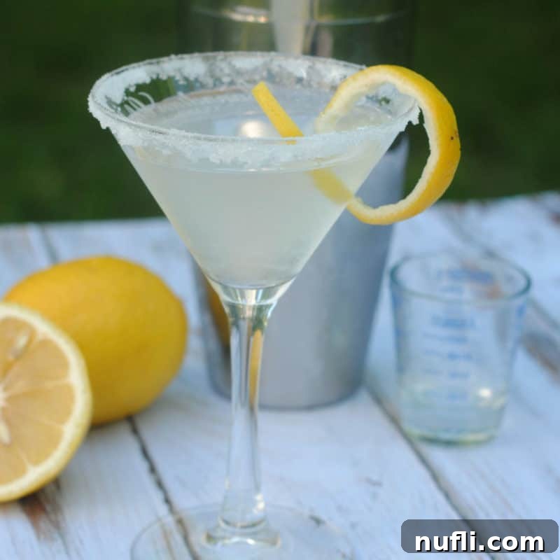Lemon Drop Martini with sugared rim next to lemons and a cocktail shaker