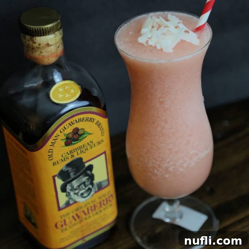 Guavaberry Colada in a hurricane glass next to a bottle of Guavaberry