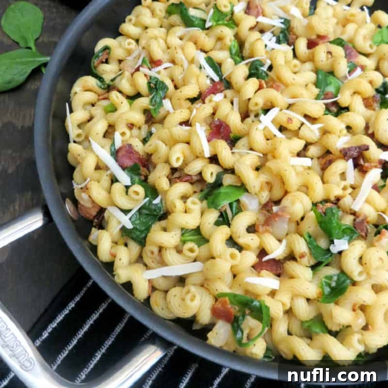 Wilted Spinach Bacon Pasta sizzling in a skillet, combining savory bacon with fresh spinach and pasta for a delicious meal.