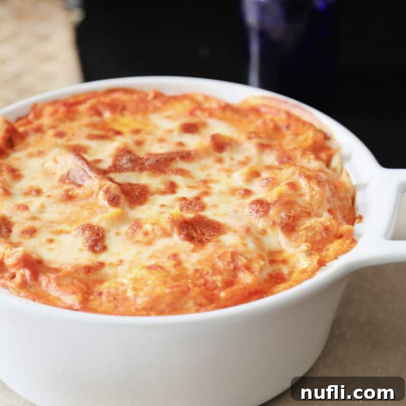 A large white casserole dish filled with bubbling, golden-brown Baked Ziti, a comforting pasta dish without meat.