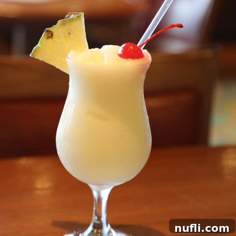 Tropical Pineapple Cocktails Made Easy 7 Pina Colada in a hurricane glass with pineapple and cherry garnish