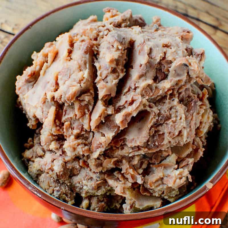 A bowl filled with rich, creamy Slow Cooker Refried Beans, a staple for any Mexican-themed meal.
