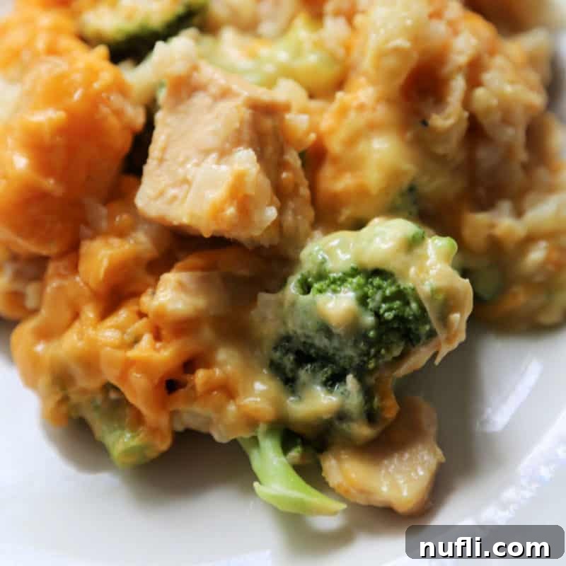 A white plate showcasing a portion of golden-brown Tater Tot Chicken Casserole with tender broccoli florets, ready to be enjoyed.