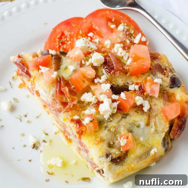 Greek Frittata on a white plate garnished with tomatoes and feta