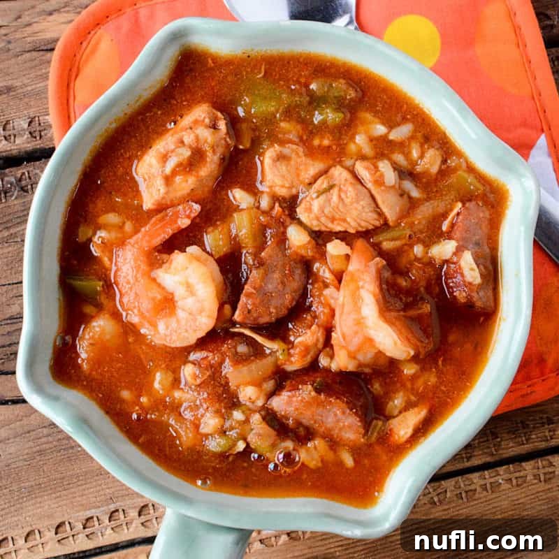A white bowl brimming with hearty Slow Cooker Gumbo, showcasing its rich broth and ingredients.