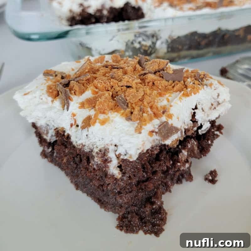 A square slice of tempting Butterfinger Poke Cake, placed next to the cake pan.